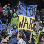 
              A Seattle Sounders supporter holds a sign that reads "Stop Wars" during a moment of silence for victims of the war in Ukraine, before the start of an MLS soccer match between the Sounders and Nashville SC, Sunday, Feb. 27, 2022, in Seattle. (AP Photo/Ted S. Warren)
            