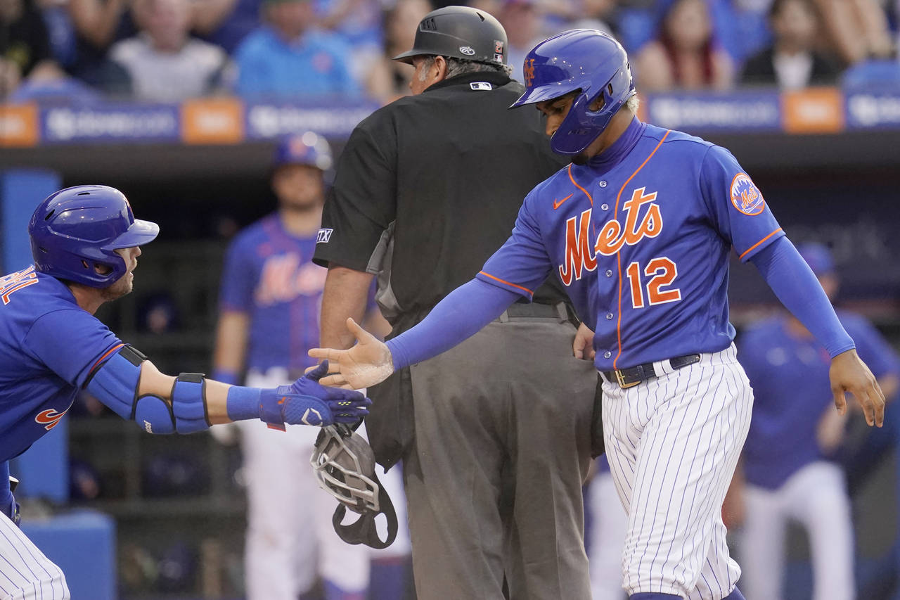 New York Mets' Jeff McNeil, left, greets teammate Francisco Lindor after Lindor scored in the third...