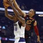 
              Dallas Mavericks forward Dorian Finney-Smith (10) grabs a rebound next to Cleveland Cavaliers guard Isaac Okoro (35) during the first half of an NBA basketball game Wednesday, March 30, 2022, in Cleveland. (AP Photo/Ron Schwane)
            