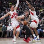
              Brooklyn Nets guard Goran Dragic (9) squeezes past Toronto Raptors guard Malachi Flynn (22) and forward Thaddeus Young (21) during the second half of an NBA basketball game Tuesday, March 1, 2022, in Toronto. (Nathan Denette/The Canadian Press via AP)
            