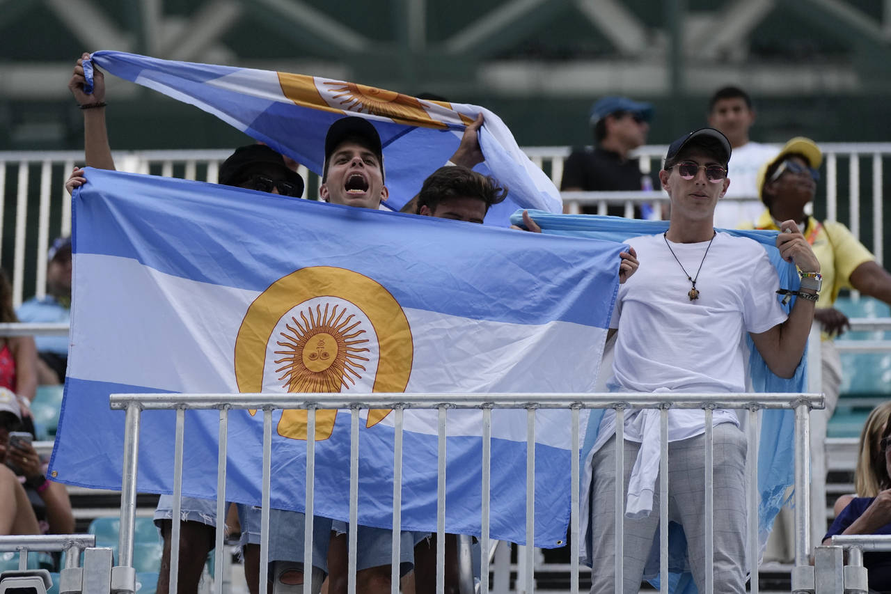 Young men hold Argentine flags, some modified with the logo of the Ultra Music Festival, as they ch...