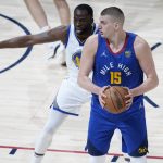 
              Denver Nuggets center Nikola Jokic, front, looks to pass the ball as Golden State Warriors forward Draymond Green defends in the first half of Game 3 of an NBA basketball first-round Western Conference playoff series Thursday, April 21, 2022, in Denver. (AP Photo/David Zalubowski)
            