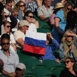 
              FILE - A spectator holding a Russian flag watches during the men's singles third round match between Russia's Daniil Medvedev and Croatia's Marin Cilic on day six of the Wimbledon Tennis Championships in London, Saturday July 3, 2021. Tennis players from Russia and Belarus will not be allowed to play at Wimbledon this year because of the war in Ukraine, the All England Club announced Wednesday, April 20, 2022.(AP Photo/Alberto Pezzali, File)
            