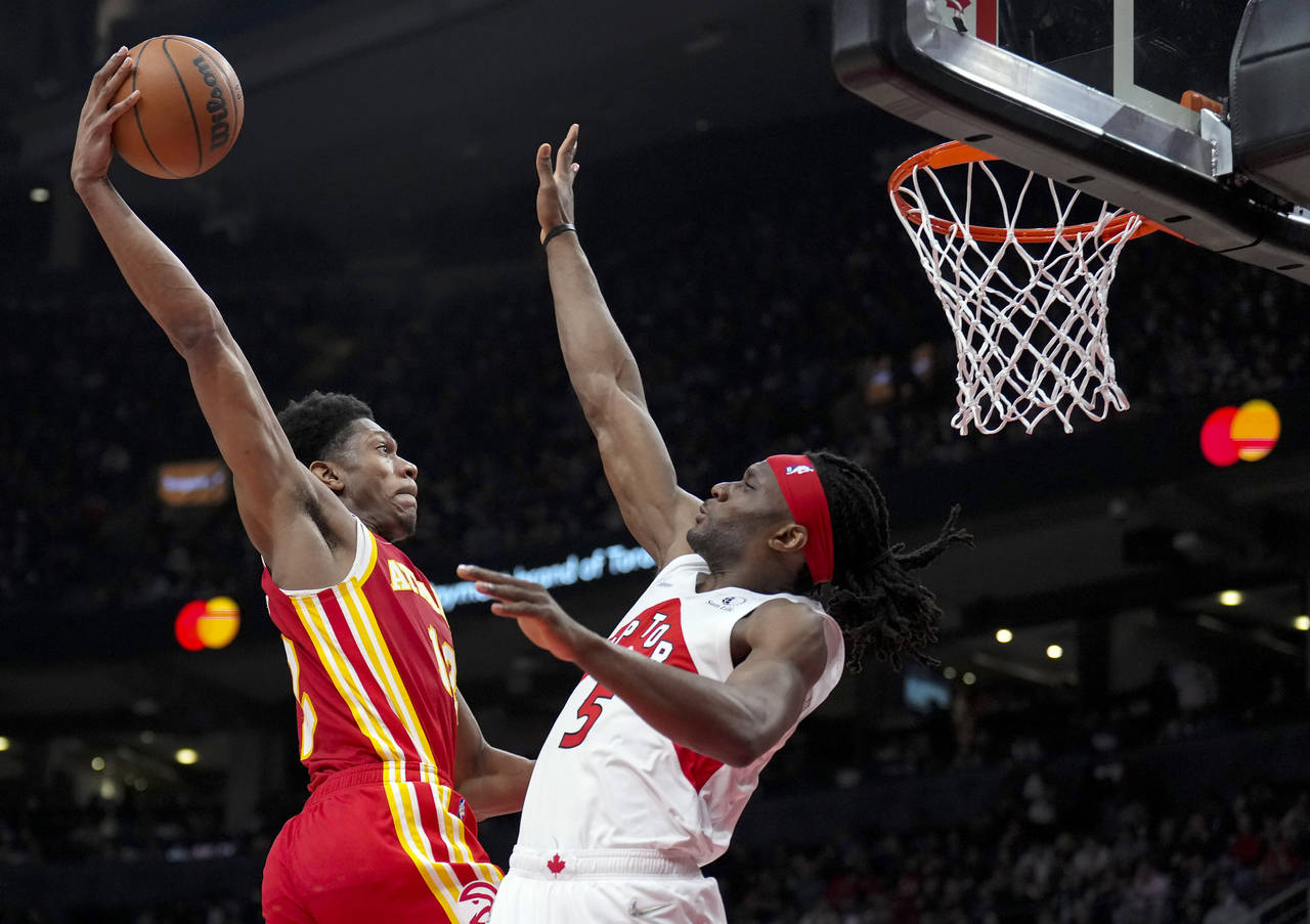 Atlanta Hawks forward De'Andre Hunter (12) tries to dunk over Toronto Raptors forward Precious Achi...