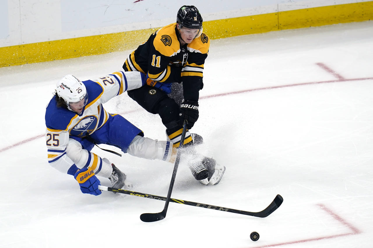 Boston Bruins center Trent Frederic (11) and Buffalo Sabres defenseman Owen Power (25) try to contr...