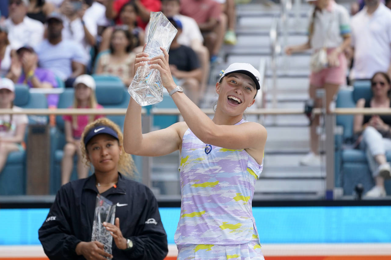 Iga Swiatek, right, of Poland, holds up her trophy after beating Naomi Osaka of Japan, left, 6-4, 6...