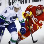 
              Vancouver Canucks defenseman Travis Dermott, left, gets past Calgary Flames left wing Andrew Mangiapane during the first period of an NHL hockey game Saturday, April 23, 2022, in Calgary, Alberta. (Jeff McIntosh/The Canadian Press via AP)
            
