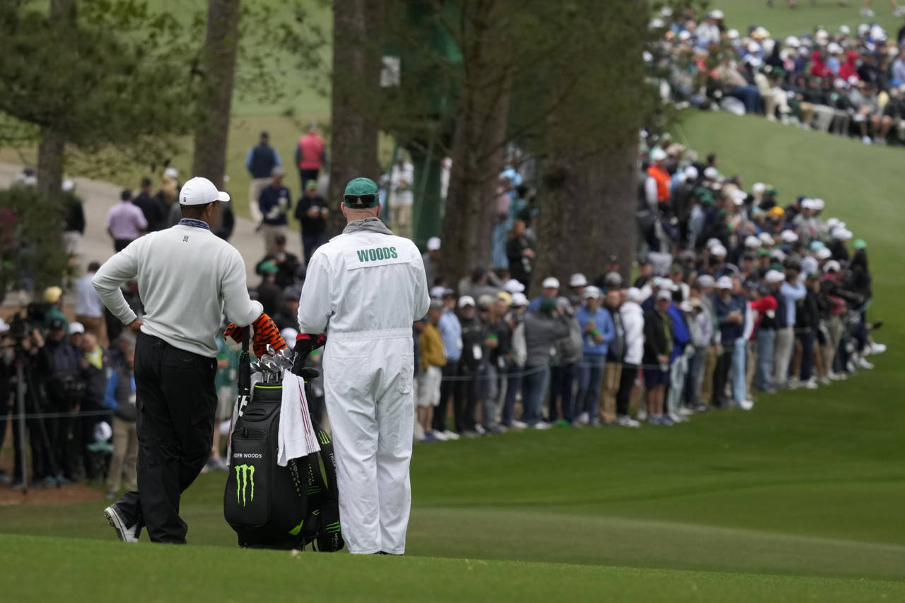Tiger Woods waits with his caddie Joe LaCava to hit on the second fairway during the third round at...