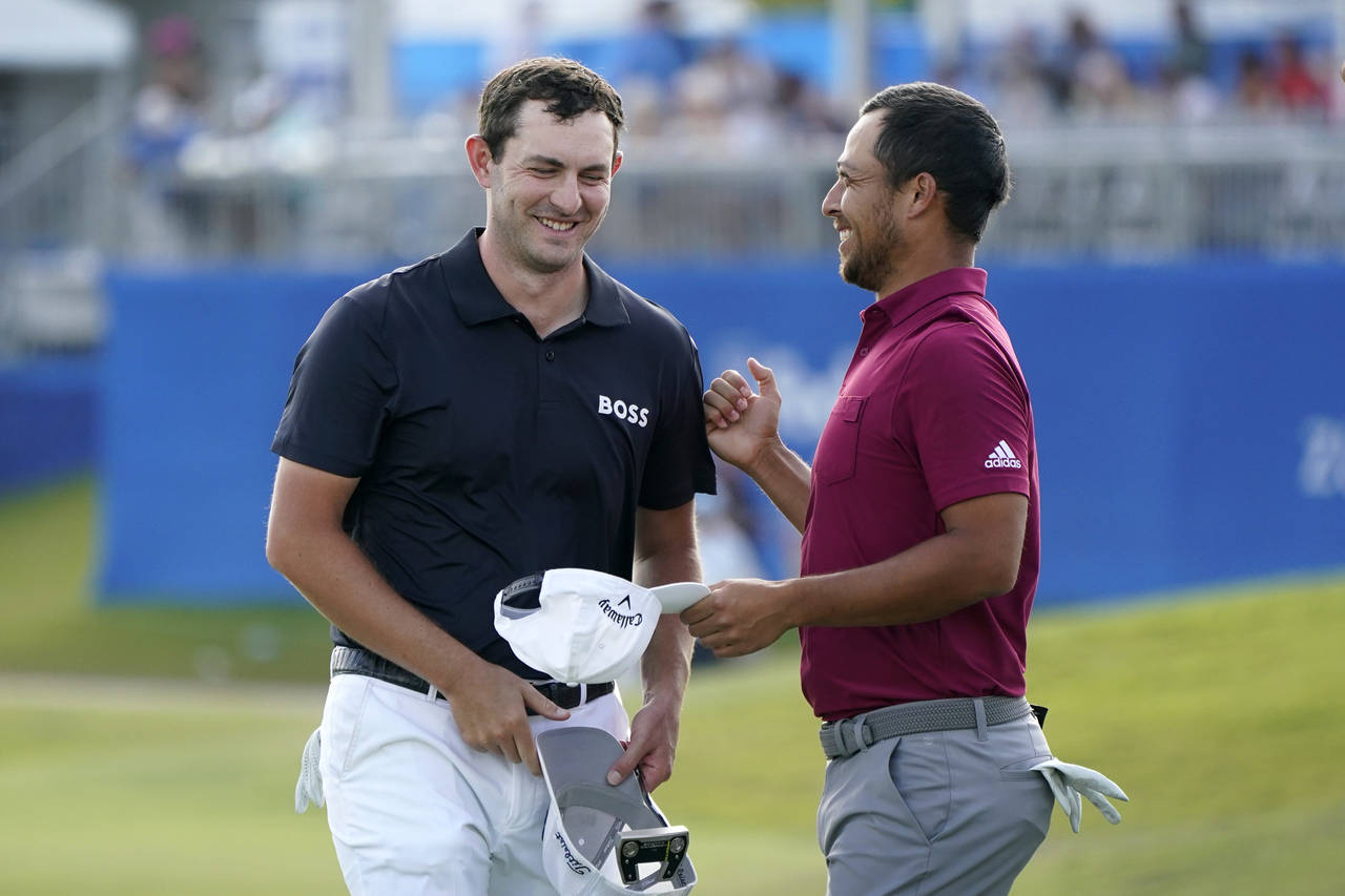Patrick Cantlay greets teammate Xander Schauffele, right, on the 18th green after completing their ...