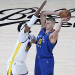 
              Denver Nuggets center Nikola Jokic, right, looks to pass the ball as Golden State Warriors center Kevon Looney defends in the first half of Game 3 of an NBA basketball first-round Western Conference playoff series Thursday, April 21, 2022, in Denver. (AP Photo/David Zalubowski)
            