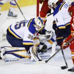 
              St. Louis Blues goalie Ville Husso, left, blocks a shot by Calgary Flames' Elias Lindholm, right, during first-period NHL hockey game action in Calgary, Alberta, Saturday, April 2, 2022. (Jeff McIntosh/The Canadian Press via AP)
            