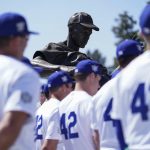 
              A statue of Jackie Robinson is seen above Los Angeles Dodgers players while they listen to David Robinson, son of Jackie Robinson, speak before a baseball game between the Cincinnati Reds and the Los Angeles Dodgers in Los Angeles, Friday, April 15, 2022. Today MLB celebrates Jackie Robinson Day, in honor of Robinson, who was the first African American to play in the major leagues. All players wore jersey number 42. (AP Photo/Ashley Landis)
            