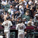 
              Fans cheer as San Francisco Giants' Wilmer Flores (41) and Brandon Crawford (35) head into the dugout after scoring against the Washington Nationals during the third inning of a baseball game in San Francisco, Saturday, April 30, 2022. (AP Photo/John Hefti)
            