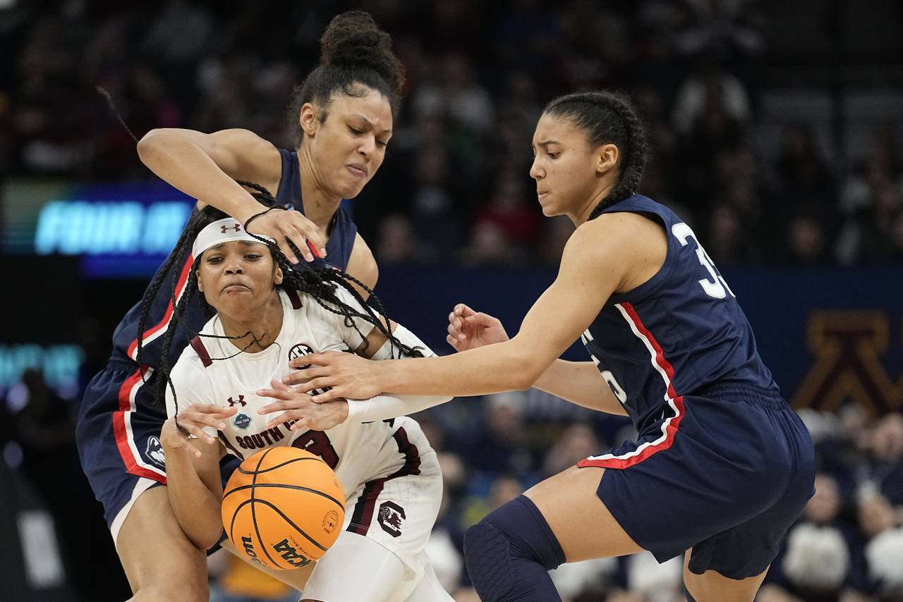 South Carolina's Destanni Henderson is fouled as she drives between UConn's Olivia Nelson-Ododa and...