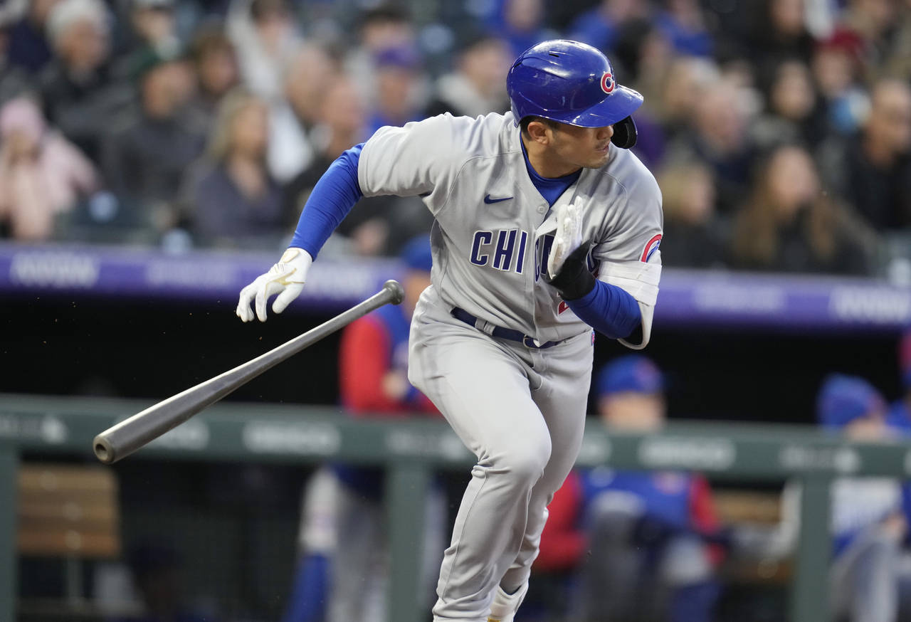 Chicago Cubs' Seiya Suzuki heads to first base as Colorado Rockies shortstop Jose Iglesias mishandl...