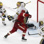 
              Denver's Carter Savoie (8) gathers the puck for the winning goal on Michigan's Erik Portillo (1) in overtime during an NCAA men's Frozen Four semifinal hockey game, Thursday, April 7, 2022, in Boston. (AP Photo/Michael Dwyer)
            