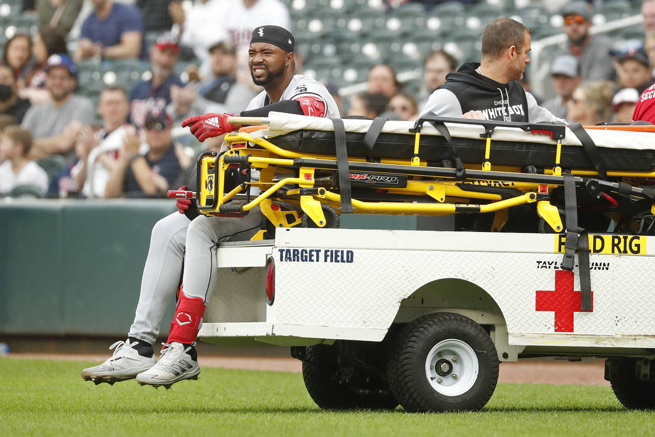 Chicago White Sox's Eloy Jimenez leaves the field on a cart after falling to the turf on a groundou...