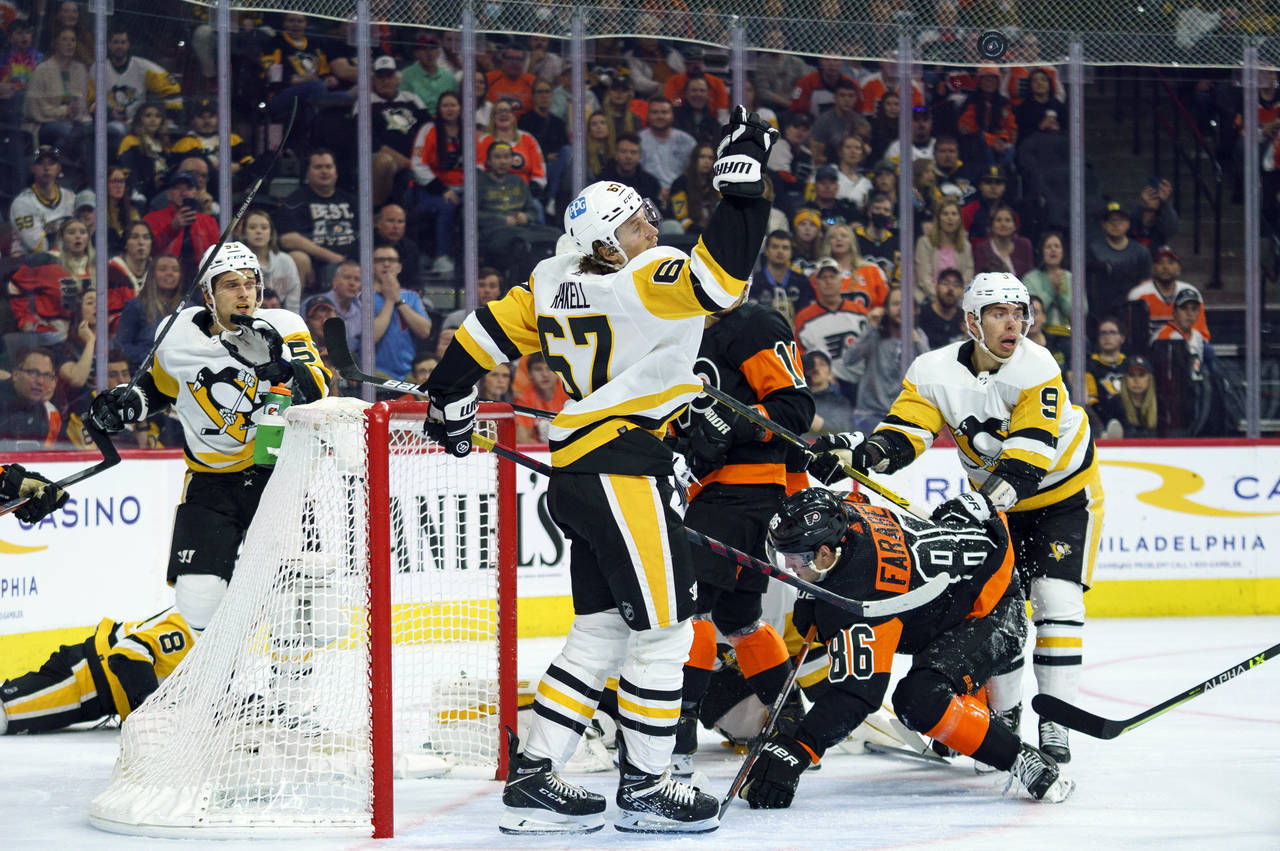Pittsburgh Penguins' Rickard Rakell, center, reaches up for the puck during the second period of an...
