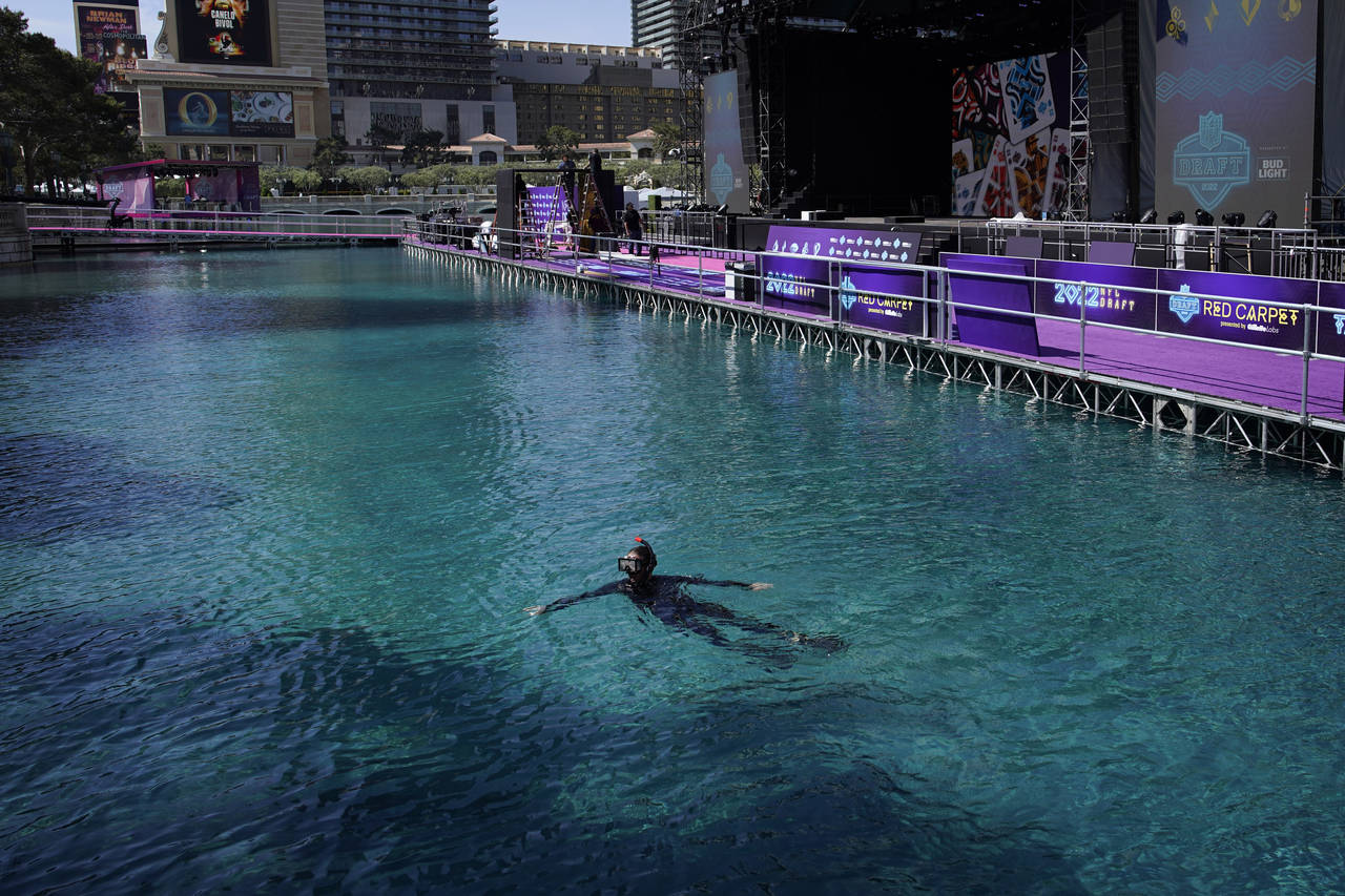 A worker swims in the fountain of the Bellagio hotel-casino during setup for the NFL football draft...