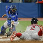 
              Boston Red Sox's Xander Bogaerts (2) scores as Toronto Blue Jays catcher Tyler Heineman tries to make the tag during the first inning of a baseball game Wednesday, April 27, 2022, in Toronto. (Christopher Katsarov/The Canadian Press via AP)
            