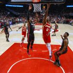 
              Atlanta Hawks' Delon Wright (0) shoots next to Miami Heat's Bam Adebayo (13) as Heat's Kyle Lowry, right, watches during the first half of Game 3 of an NBA basketball first-round playoff series Friday, April 22, 2022, in Atlanta. (AP Photo/Brett Davis)
            