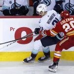 Seattle Kraken center Alex Wennberg (21) is knocked off the puck by Calgary Flames center Blake Coleman (20) during the second period of an NHL hockey game Tuesday, April 12, 2022, in Calgary, Alberta. (Larry MacDougal/The Canadian Press via AP)