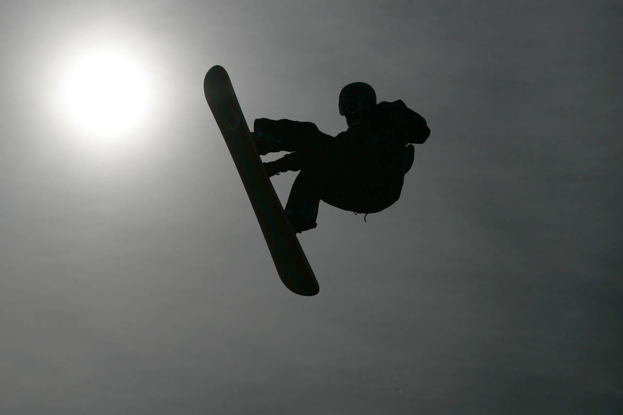 FILE - A silhouette of a snowboarder in action in a heat during the FIS World Cup snowboarding big ...