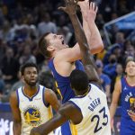 
              Denver Nuggets center Nikola Jokic, top, shoots over Golden State Warriors forward Draymond Green (23) during the first half of Game 2 of an NBA basketball first-round playoff series in San Francisco, Monday, April 18, 2022. (AP Photo/Jeff Chiu)
            