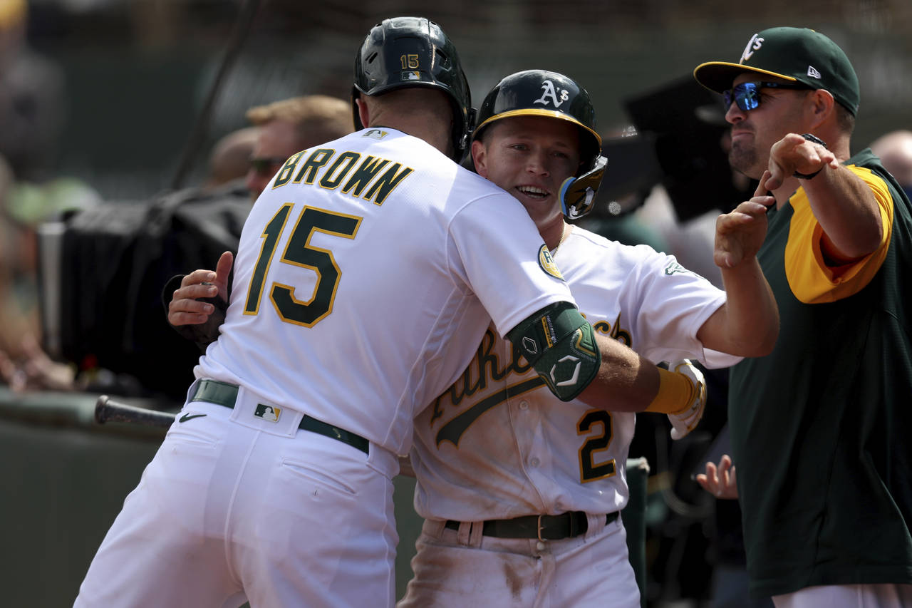 Oakland Athletics' Nick Allen (2) is congratulated by Seth Brown (15) after scoring on a single by ...