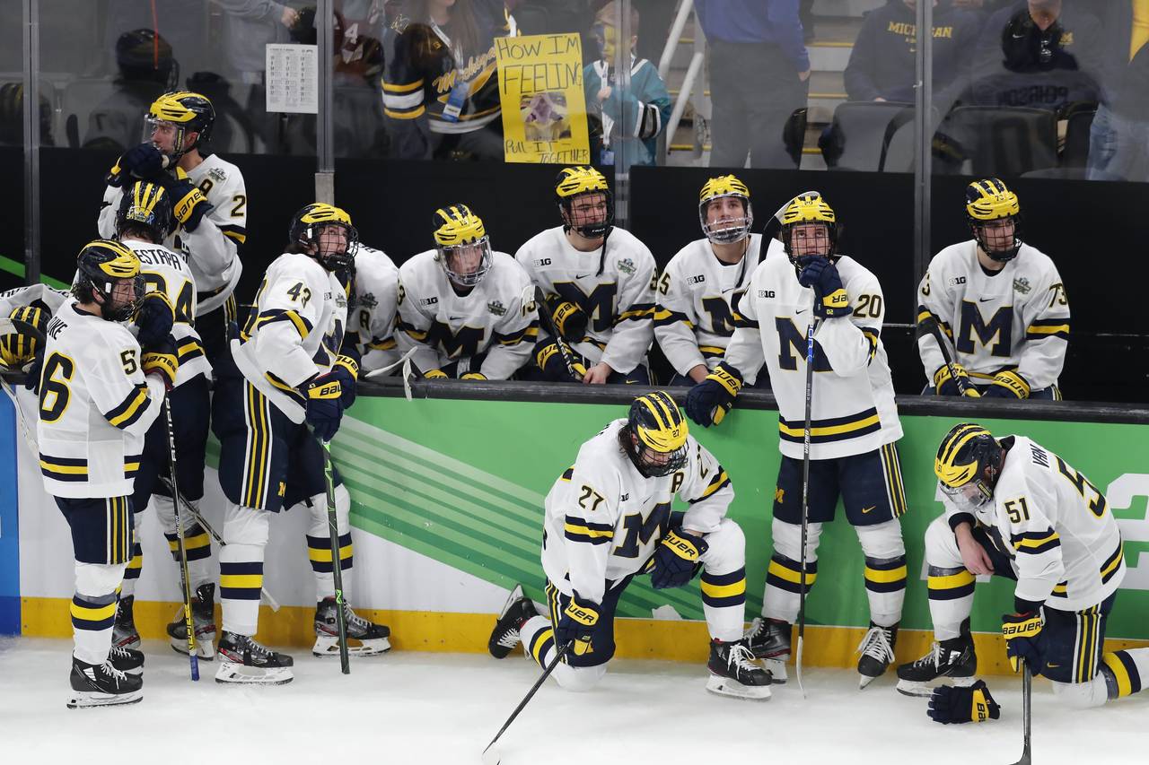 Michigan players react after losing to Denver in overtime during an NCAA men's Frozen Four semifina...