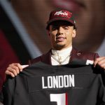 
              Southern California wide receiver Drake London holds a jersey after being chosen by the Atlanta Falcons with the eighth pick of the NFL football draft Thursday, April 28, 2022, in Las Vegas. (AP Photo/John Locher)
            
