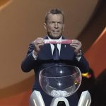 
              Former German soccer international and manager Lothar Matthaus holds up the name of the United States during the 2022 soccer World Cup draw at the Doha Exhibition and Convention Center in Doha, Qatar, Friday, April 1, 2022. (AP Photo/Hassan Ammar)
            