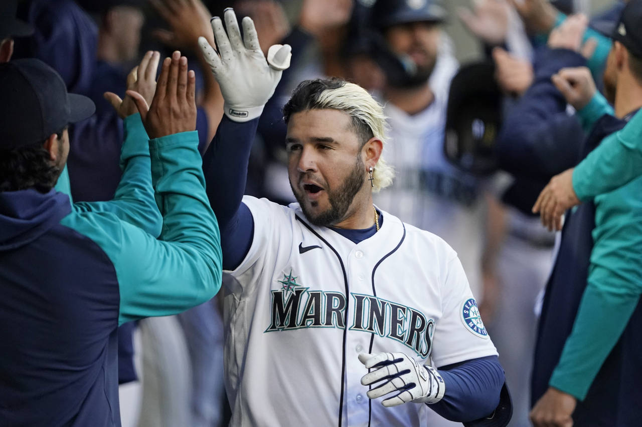 Seattle Mariners' Eugenio Suarez is greeted in the dugout after he hit a three-run home run against...
