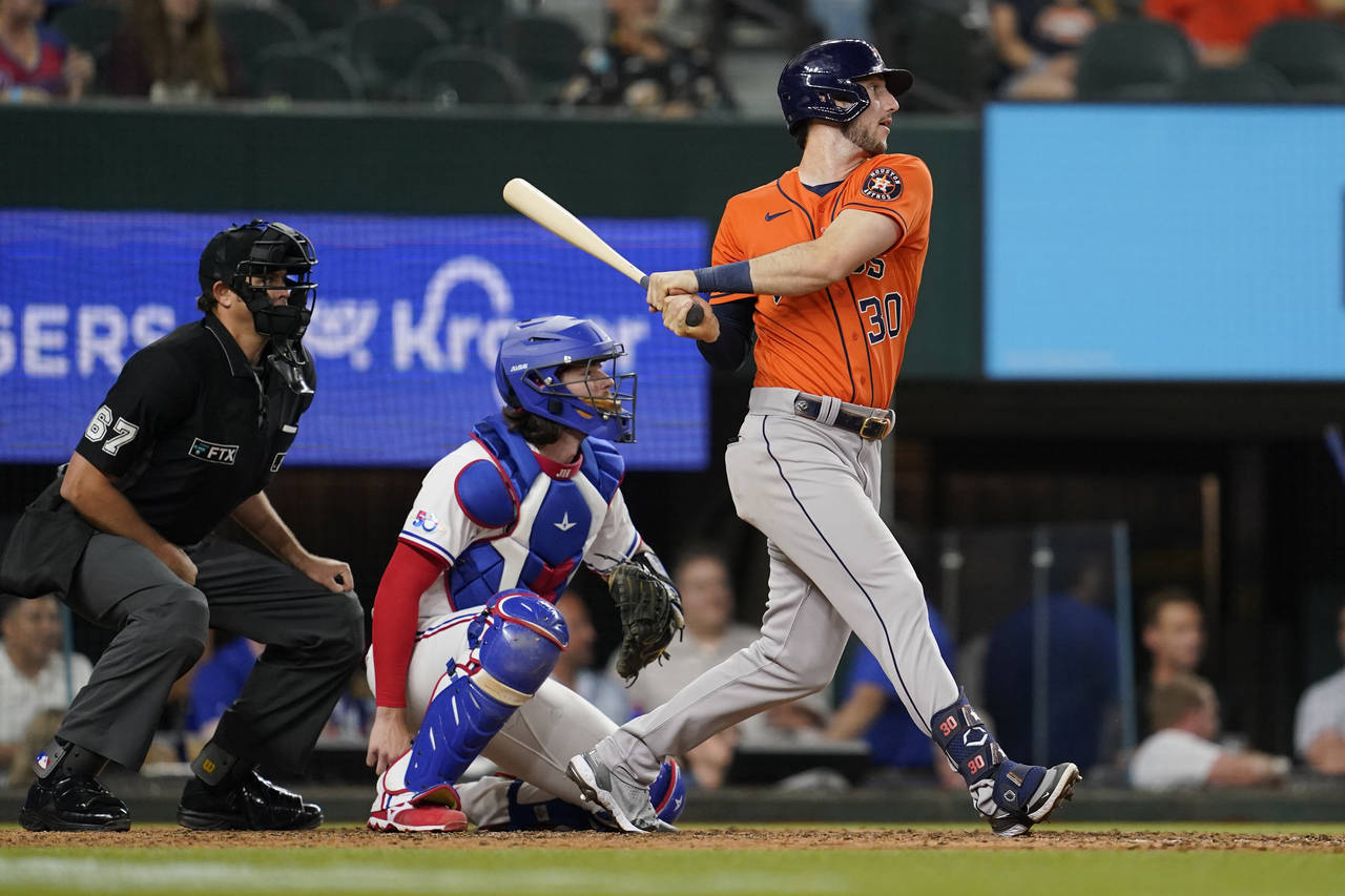 Houston Astros' Kyle Tucker comes around on his swing in front of Texas Rangers' Jonah Heim, center...