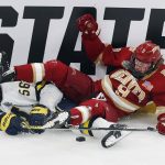 
              Denver's Owen Ozar (9) and Michigan's Dylan Duke (56) battle for the puck during the first period of an NCAA men's Frozen Four semifinal hockey game, Thursday, April 7, 2022, in Boston. (AP Photo/Michael Dwyer)
            