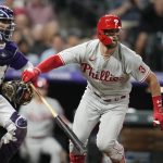 
              Philadelphia Phillies' Bryce Harper, right, breaks from the batter's box on a groundout, next to Colorado Rockies catcher Elias Diaz during the fifth inning of a baseball game Tuesday, April 19, 2022, in Denver. (AP Photo/David Zalubowski)
            