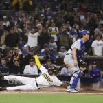 
              San Diego Padres' C.J. Abrams, left, scores the winning run on an Austin Nola sacrifice fly, next to Los Angeles Dodgers catcher Will Smith during the 10th inning of a baseball game Saturday, April 23, 2022, in San Diego. (AP Photo/Derrick Tuskan)
            
