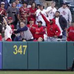 
              Fans try to catch a ball hit for a two-run home run by Los Angeles Angels' Anthony Rendon as Miami Marlins center fielder Bryan De La Cruz watches during the sixth inning of a baseball game Tuesday, April 12, 2022, in Anaheim, Calif. (AP Photo/Mark J. Terrill)
            