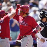 
              Philadelphia Phillies' Kyle Schwarber, left, congratulates Alec Bohm as he crosses home plate after hitting a two-run home run as Colorado Rockies catcher Dom Nunez waits for play to resume in the fourth inning of a baseball game Wednesday, April 20, 2022, in Denver. (AP Photo/David Zalubowski)
            