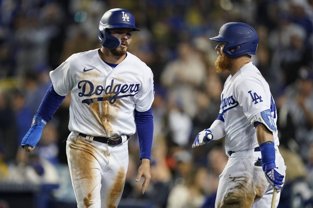 Los Angeles Dodgers' Gavin Lux, left, celebrates with Justin Turner after scoring off of a triple h...