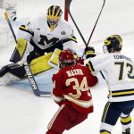
              Michigan's Erik Portillo (1) blocks a shot under pressure from Denver's Carter Mazur (34) as Ethan Edwards (73) defends during the first period of an NCAA men's Frozen Four semifinal hockey game, Thursday, April 7, 2022, in Boston. (AP Photo/Michael Dwyer)
            