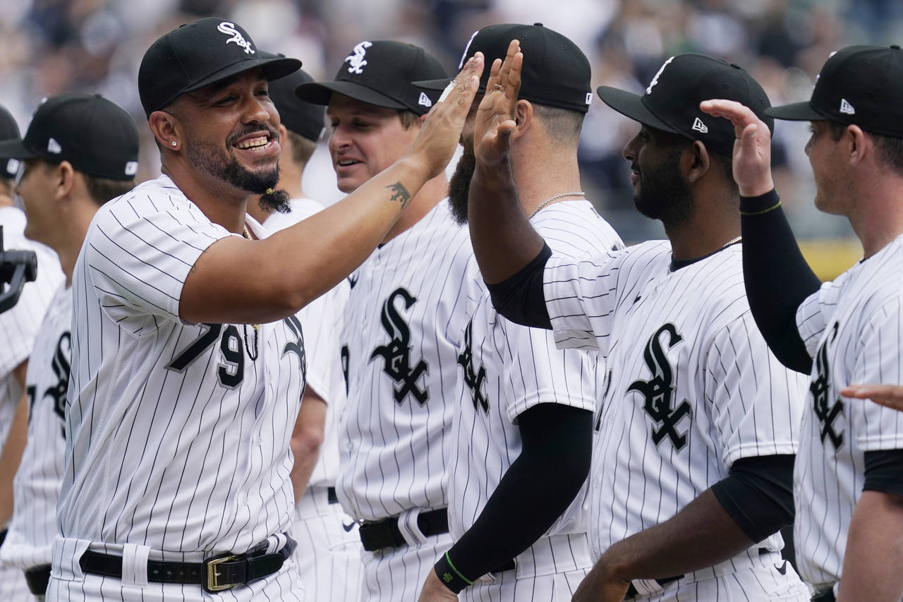 Chicago White Sox's Jose Abreu, left, greets teammates as he runs on the field during an opening da...