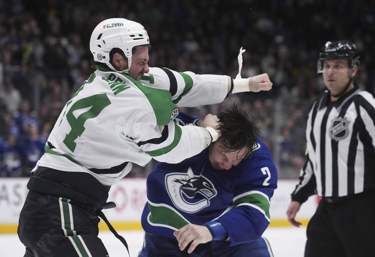 Dallas Stars' Jamie Benn, left, and Vancouver Canucks' Luke Schenn fight during the second period o...