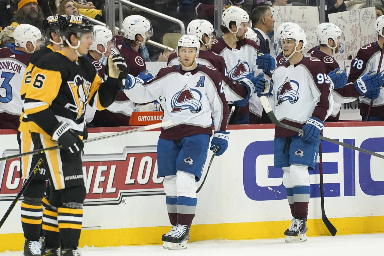 Colorado Avalanche's Nathan MacKinnon, center, celebrates with teammates on the bench after scoring...