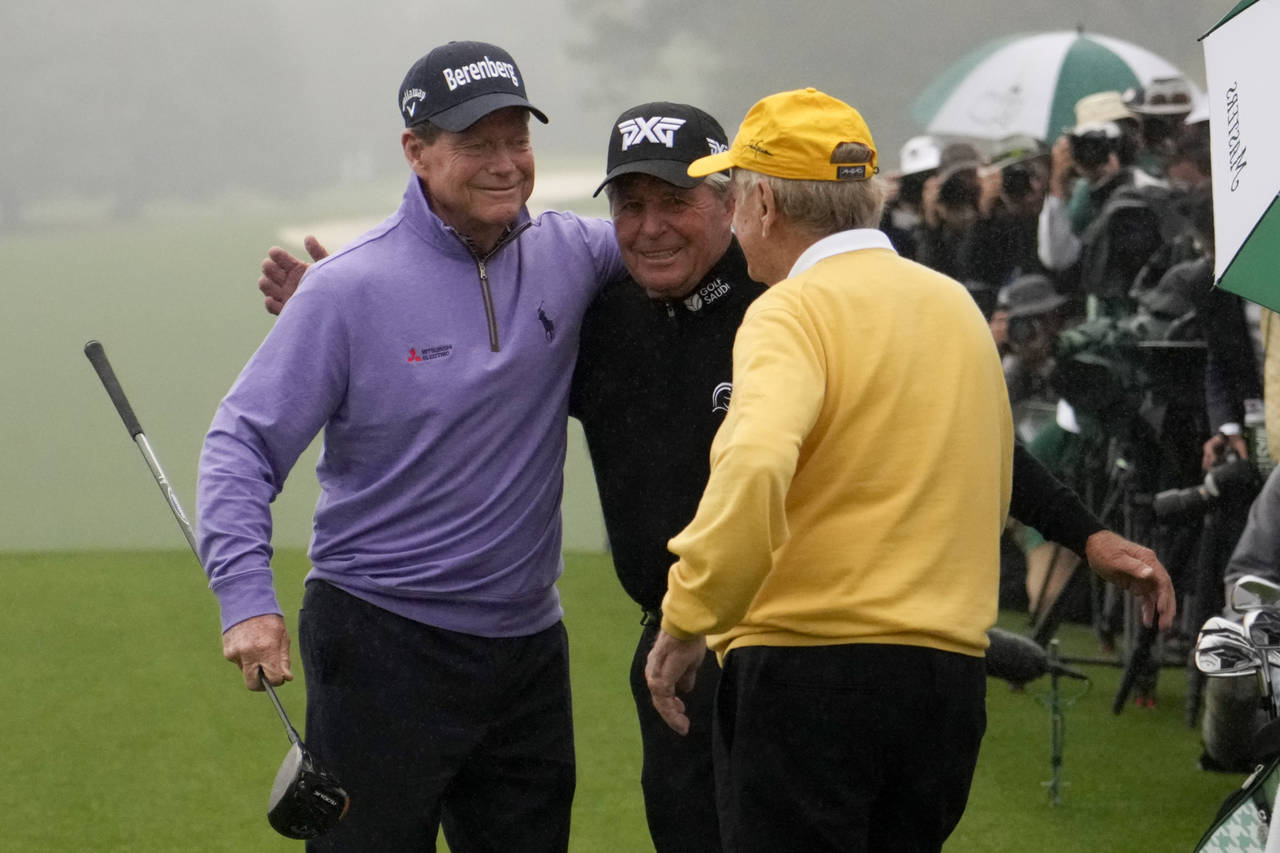 Tom Watson, left, Gary Player, and Jack Nicklaus, right, hug during the honorary starter ceremony b...