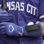 
              Kansas City Royals catcher Cam Gallagher wears a wrist-worn device used to call pitches as he prepares to bat during the sixth inning of a spring training baseball game against the Seattle Mariners, Tuesday, March 29, 2022, in Peoria, Ariz. The MLB is experimenting with the PitchCom system where the catcher enters information on a wrist band with nine buttons which is transmitted to the pitcher to call a pitch. (AP Photo/Charlie Riedel)
            
