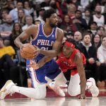 
              Toronto Raptors forward Precious Achiuwa, right, looks to steal the ball from Philadelphia 76ers center Joel Embiid (21) during the first half of an NBA basketball game Thursday, April 7, 2022, in Toronto. (Frank Gunn/The Canadian Press via AP)
            