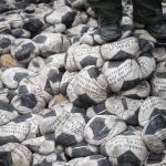 
              A person stands on a part of 6,500 soccer balls filled with sand and dropped by German artist Volker-Johannes Trieb in front of the headquarters of the world football's governing body FIFA in Zurich, Switzerland, Friday, April 1, 2022. 'World conscience, you are a stain of shame' is emblazoned on the balls, which are meant to symbolize the migrant workers who have suffered through poor working conditions building the infrastructure in Qatar to stage the World Cup. (Ennio Leanza/Keystone via AP)
            