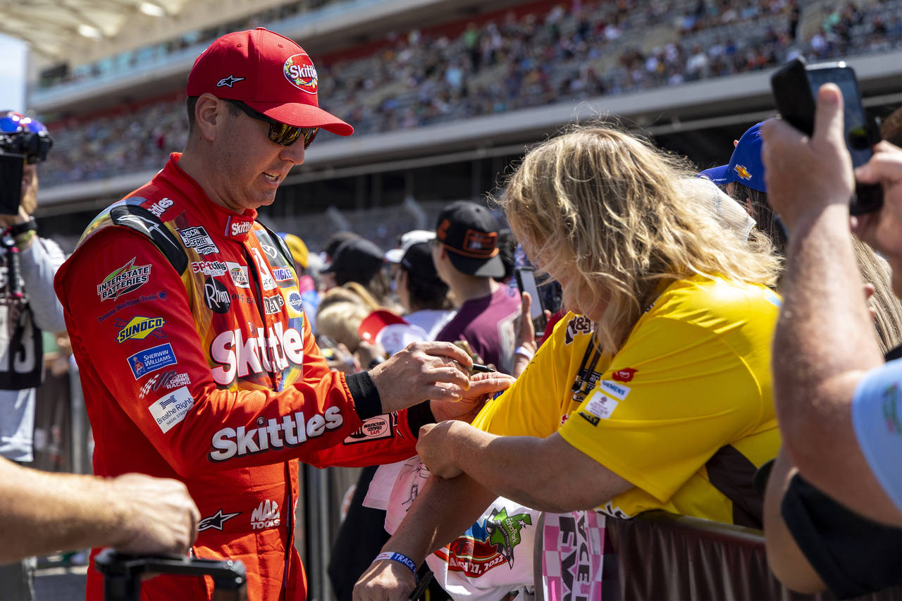 Kyle Busch, left, gives autographs before a NASCAR Cup Series auto race at Circuit of the Americas,...