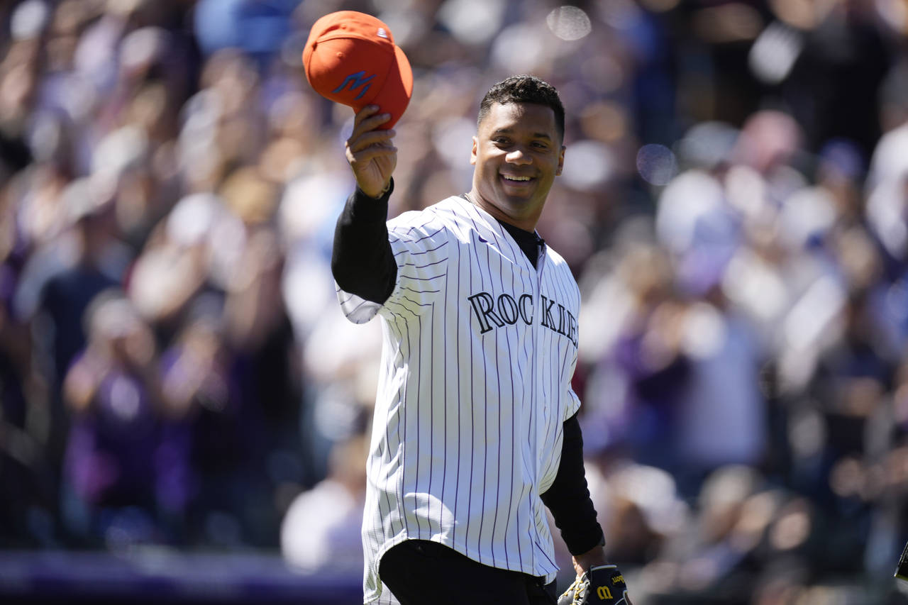 Denver Broncos quarterback Russell Wilson doffs his hat as he heads to the mound to throw out the f...